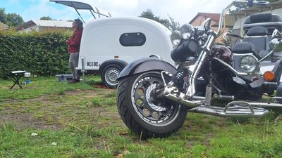 Geöffnete Heckklappe eines KLEOX shelter travel auf einer Campingwiese, davor ein Trike